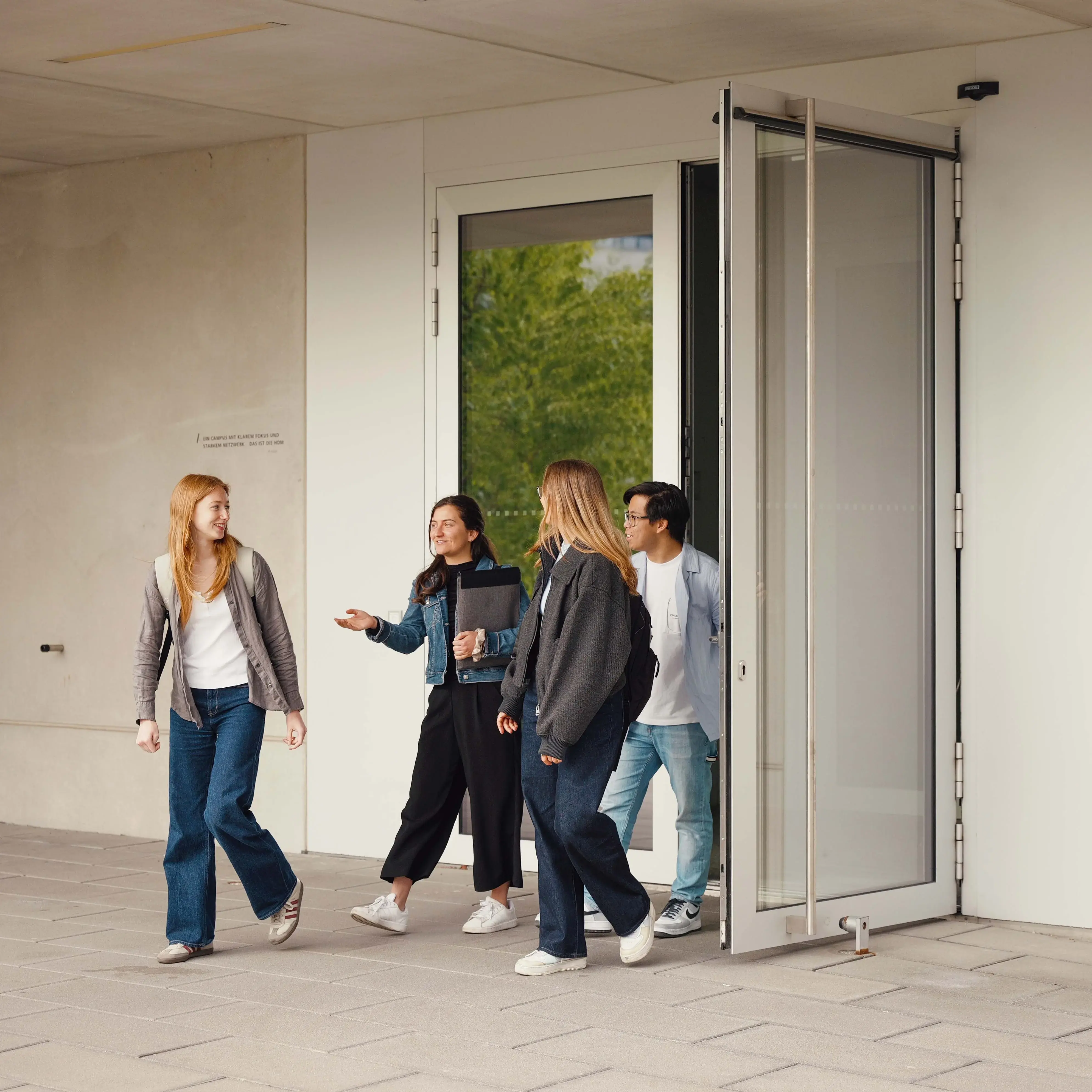 Studierende unterhalten sich beim Verlassen der Hochschule der Medien.