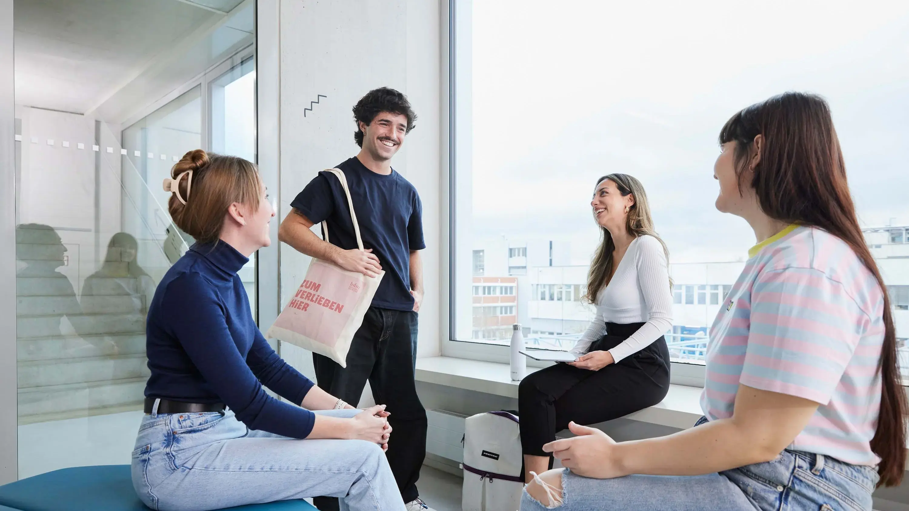 Studierende unterhalten sich auf Sitzgelegenheiten auf dem Campus der Hochschule der Medien.